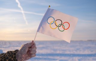 Beijing, China - 10.10.2021 - The Olympic flag, small in hand, flutters against the backdrop of snow and trees Concept for Winter Olympic Games 2022.