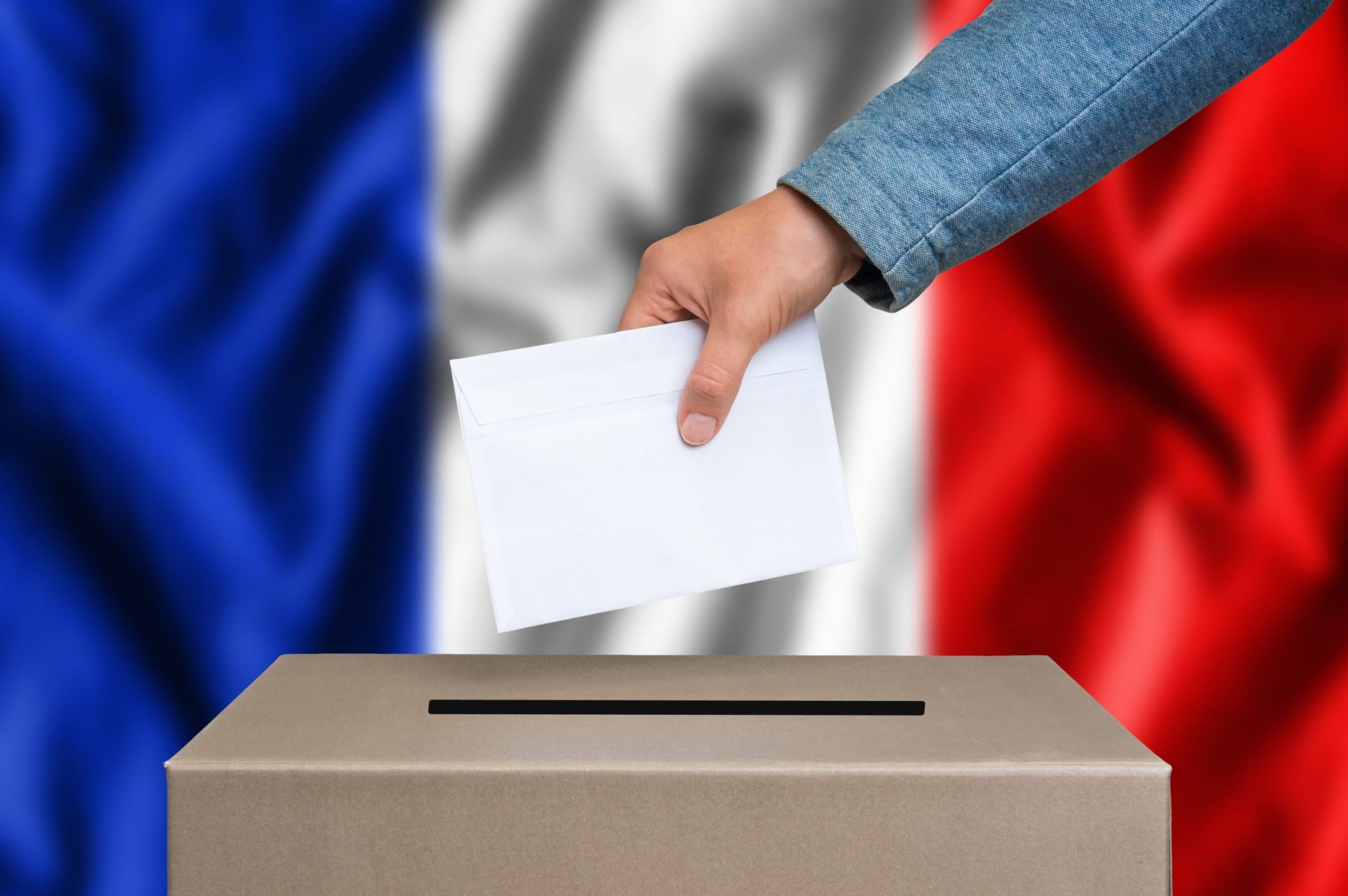 Election in France. The hand of woman putting her vote in the ballot box. French flag on background.
