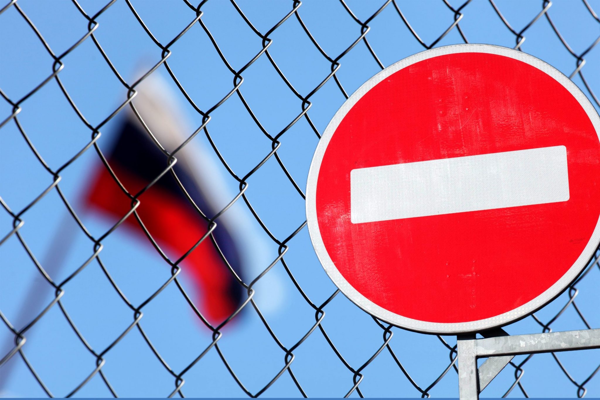 Flag of Russia behind a fence with a forbidding sign brick
