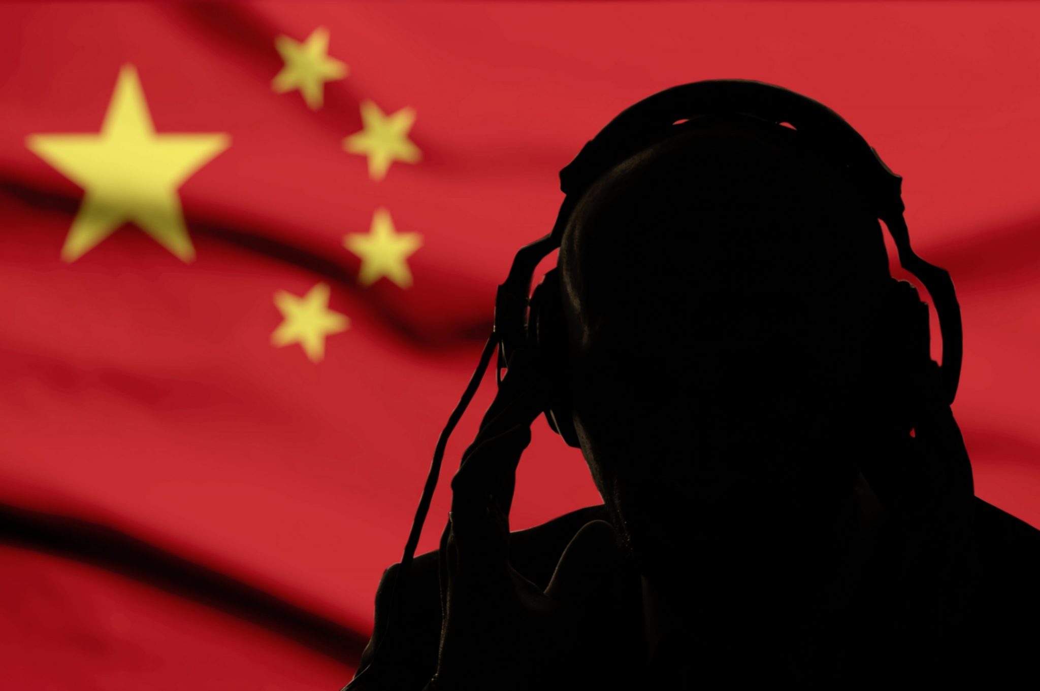 Silhouette of a man in headphones, secret agent eavesdropping, spy and scout, China flag, backlight