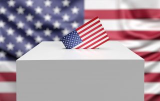 Inserting US flagged voting envelope in white ballot box on American flag background with copy space.