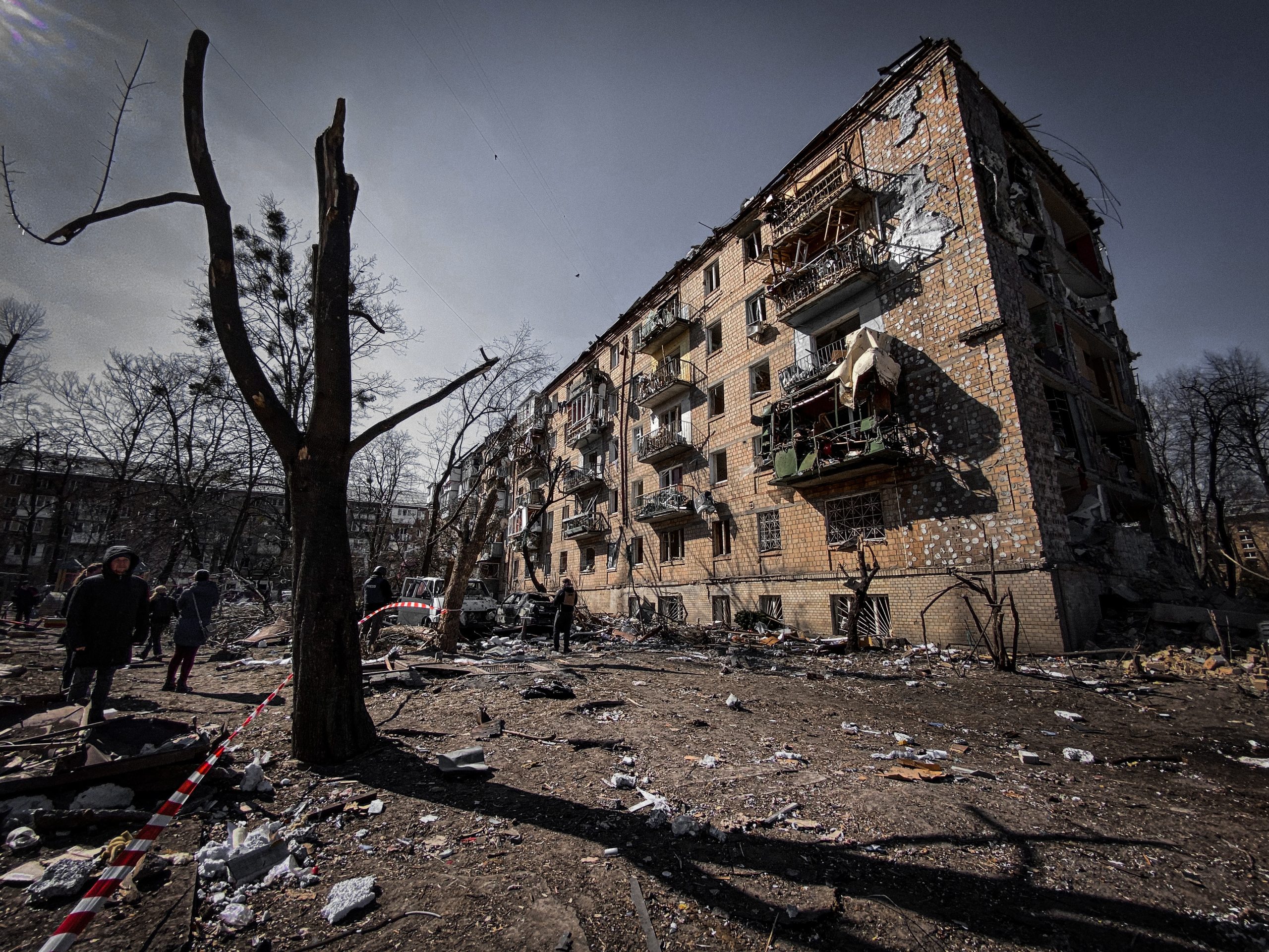 damaged building in Ukraine with soldiers walking on the side